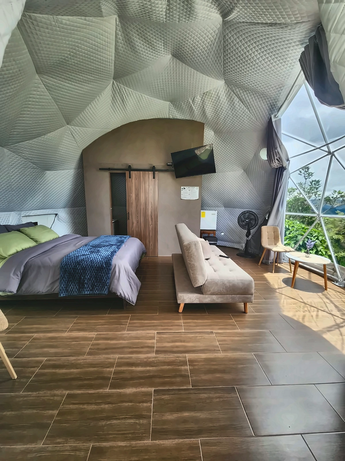 Interior del domo tipo glamping de La Finca Spa & Recepciones con luz natural, cama y vista al entorno