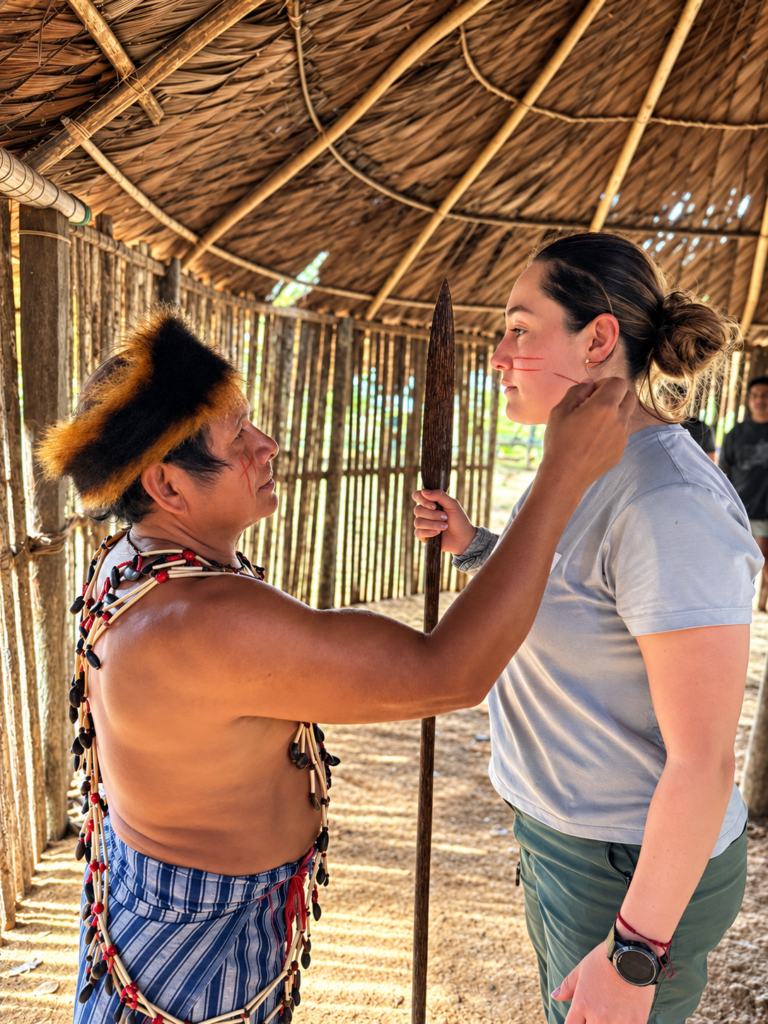 Encuentro cultural entre un anfitrión indígena y una visitante durante una experiencia amazónica